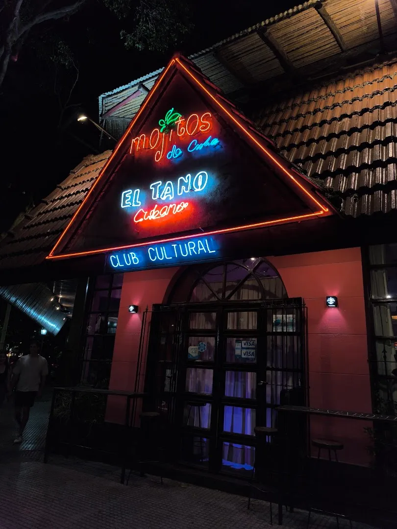 Fachada de Mojitos de Cuba de noche, con el cartel de neón El Tano Cubano y Club Cultural